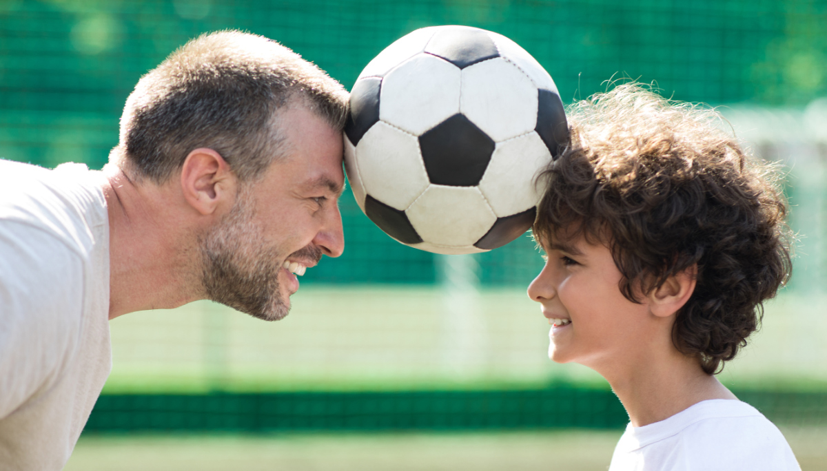 Competition Concept. Closeup of adult man and small boy holding soccer ball between forehead